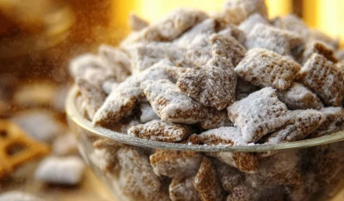 Puppy Chow Chex Mix in glass bowl with powdered sugar
