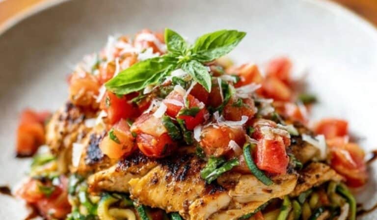 Bruschetta Chicken with Zucchini Noodles on a white plate with basil and balsamic glaze