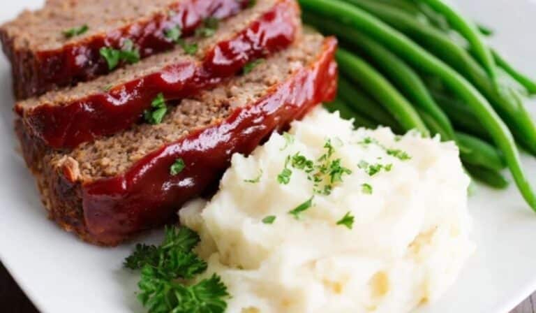 Homemade Meatloaf Recipe sliced with glossy ketchup glaze on platter