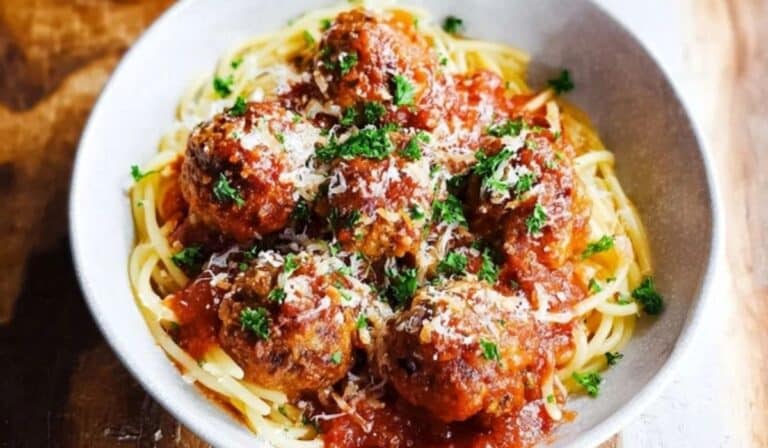Homemade meatball recipe served over spaghetti with tomato sauce and Parmesan