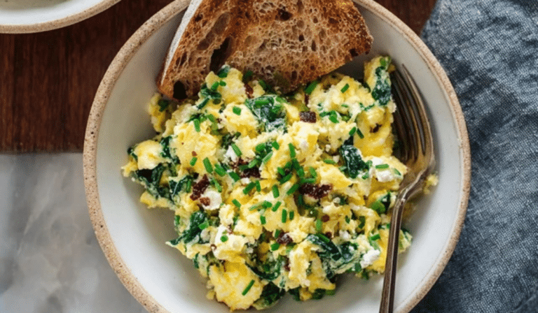 Spinach scrambled eggs with goat cheese on a plate with toast