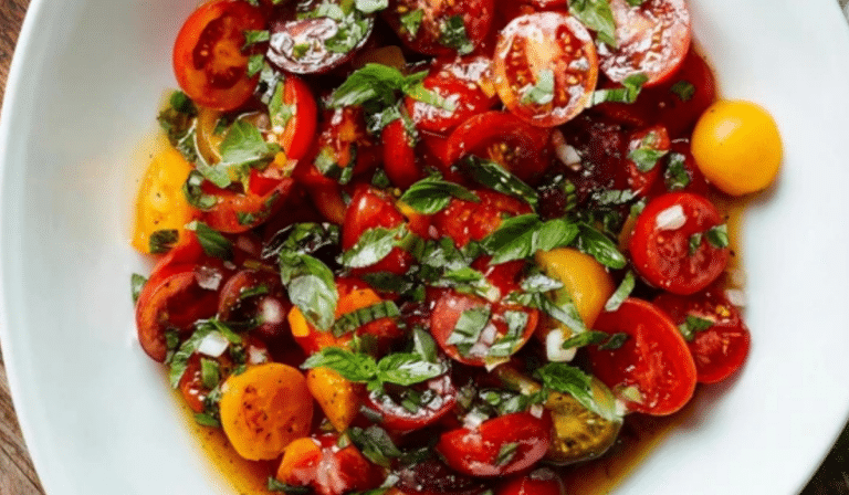 Easy Tomato Salad in a white bowl with basil and vinaigrette