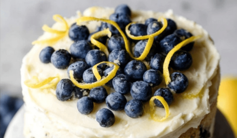 Lemon Blueberry Layer Cake slice with cream cheese frosting and fresh berries